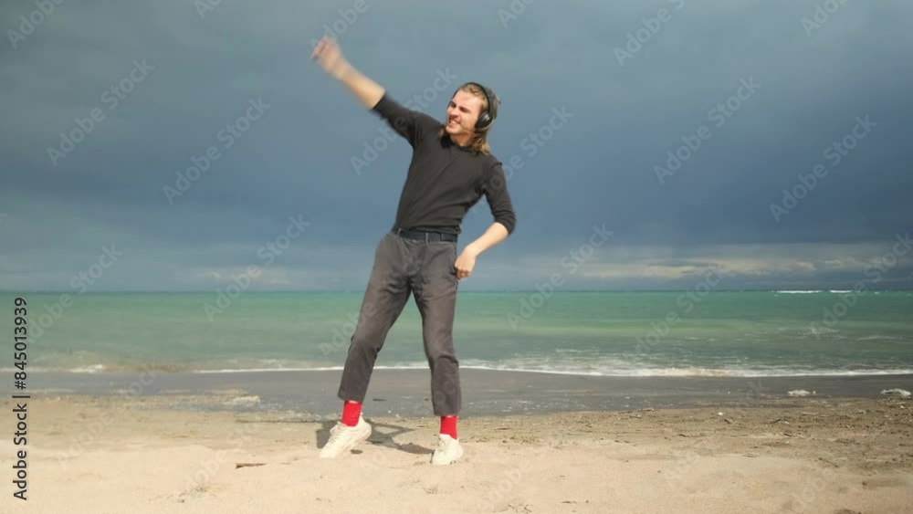 Happy man dancing on sand beach with blue sea surface background, slow motion. Copy space. Happy man dancing on sand beach with blue sea surface background, slow motion. Copy space.