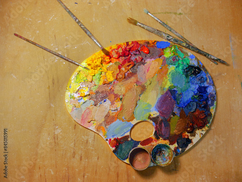 Colorful artist palette full of acrylic paint and with brushes photo