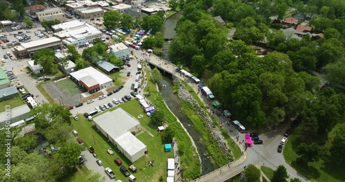 Booths And Parked Cars With People Gathering By The Sager Creek During 50th Dogwood Festival In Siloam  Springs, Arkansas. aerial photo