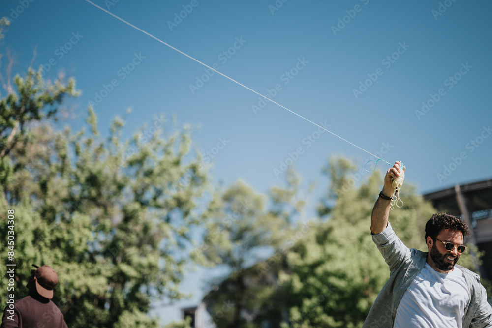 A cheerful man enjoys flying a kite outdoors in a lush park, displaying joy and happiness while friends watch. A cheerful man enjoys flying a kite outdoors in a lush park, displaying joy and happiness while friends watch.