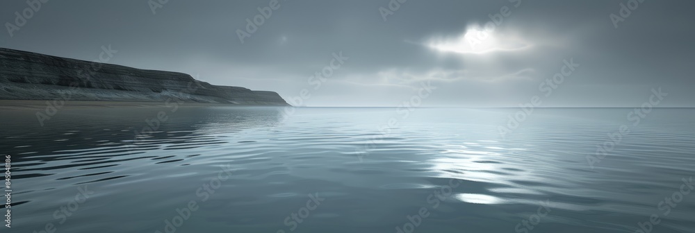 Fototapeta premium A wide shot of a calm sea with a distant cliff and a misty sky
