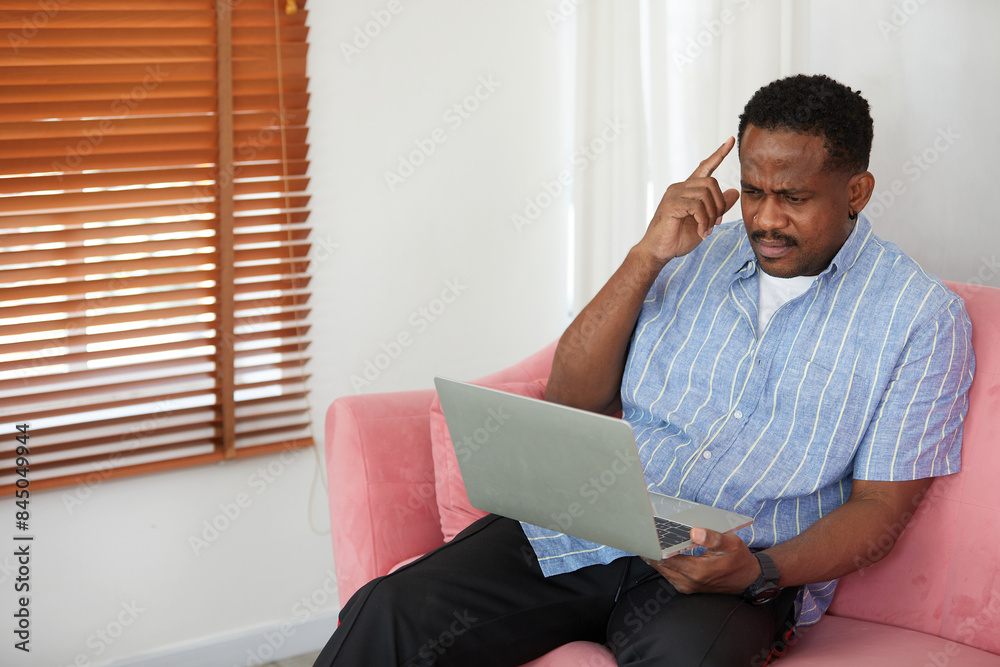 Fototapeta premium African American man working on laptop computer and thinking about work