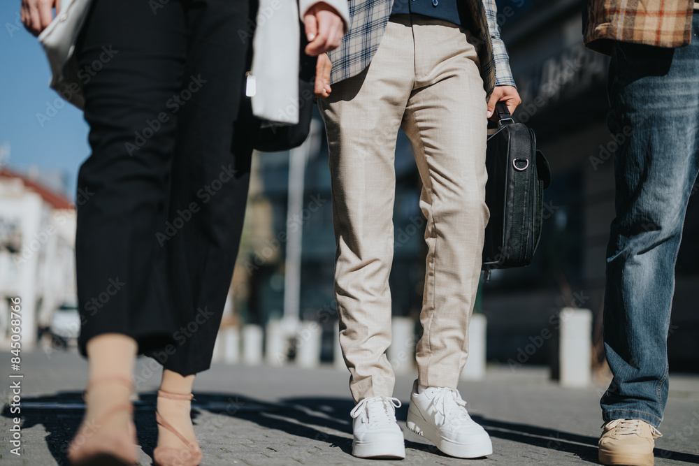 Focused on the lower half of their bodies, young business professionals stand outdoors, engaged in a strategic discussion. Focused on the lower half of their bodies, young business professionals stand outdoors, engaged in a strategic discussion.