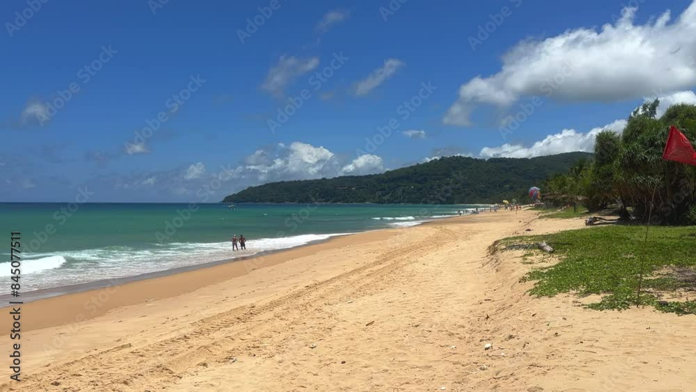 Tourists on a tropical beach enjoying beautiful turquoise seas. Turquoise ocean on a sunny summers day. Summer holidays and paradise beach concept. Karon Beach, Phuket, Thailand. Tourists on a tropical beach enjoying beautiful turquoise seas. Turquoise ocean on a sunny summers day. Summer holidays and paradise beach concept. Karon Beach, Phuket, Thailand.