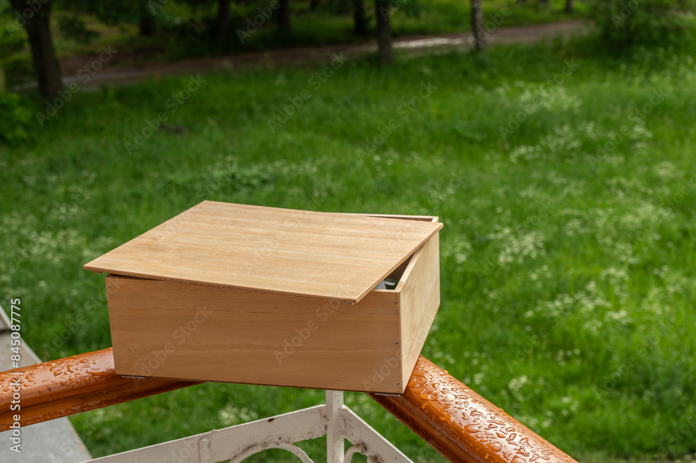 Naklejka premium The wooden gift box with cover on railing of balcony on background of summer landscape.