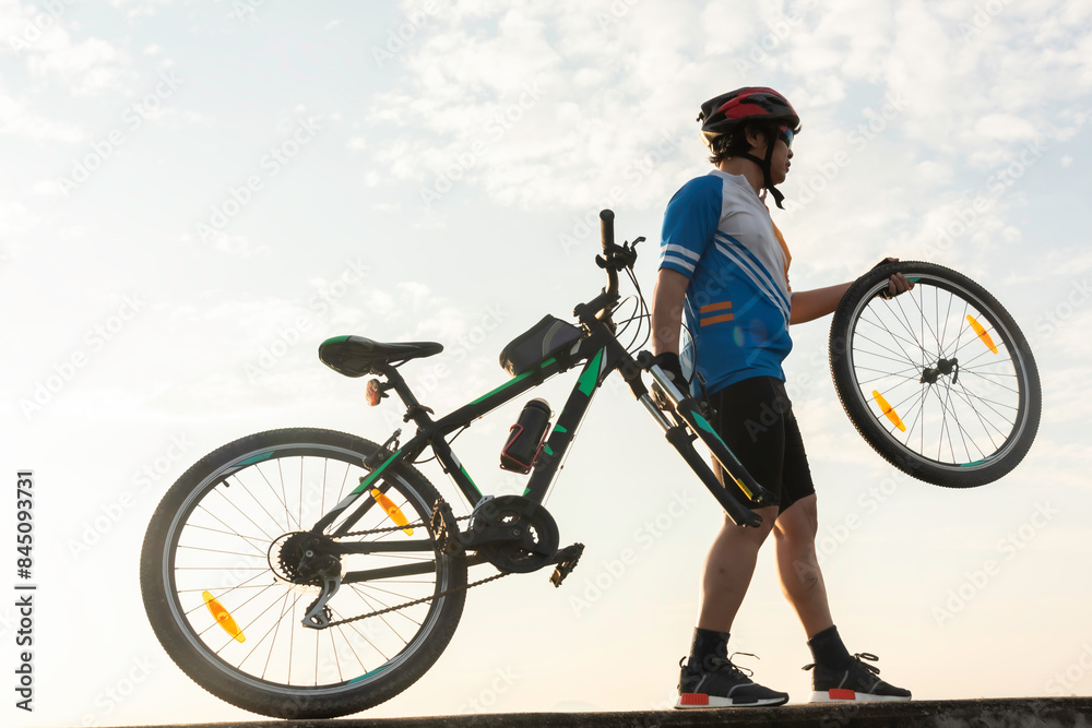 Man cyclist repairing a bike against the background of sky Man cyclist repairing a bike against the background of sky