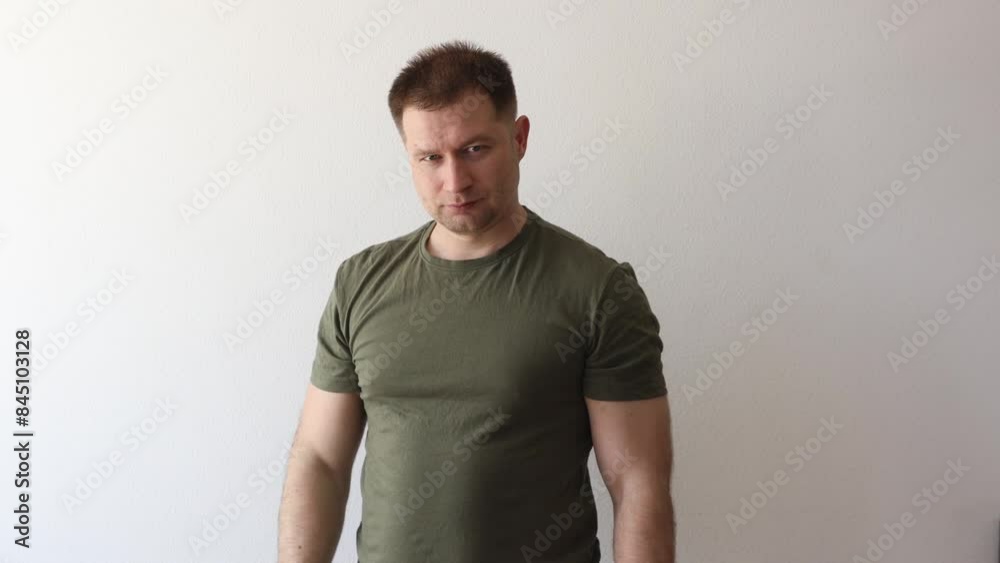 A man in a military hacky sack t-shirt salutes with his hand. A man in a military hacky sack t-shirt salutes with his hand.