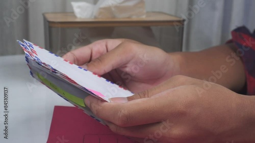 close up of hands sorting envelopes on table with red document folder