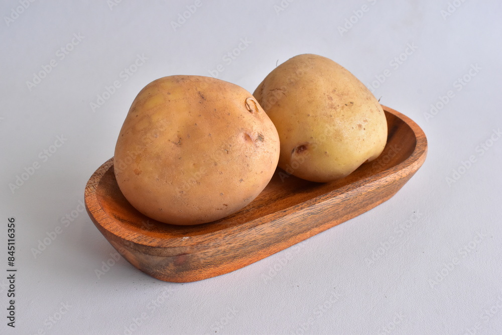 Raw potatoes in bowl on white background, close up view