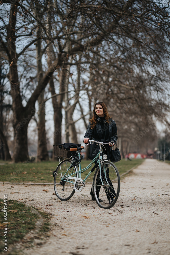 A professional woman with a bicycle stands in an urban park, exuding confidence and enjoying a leisurely moment amidst nature in the city.