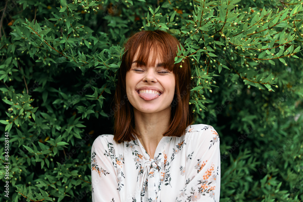 Happy woman surrounded by lush greenery with hands on face in joyful expression