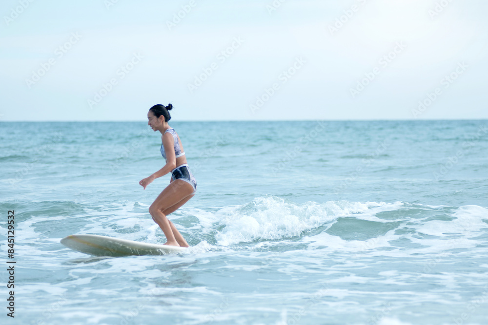 Asian surfing woman riding the waves on sunny day, outdoor activities, water sports activities concept Asian surfing woman riding the waves on sunny day, outdoor activities, water sports activities concept