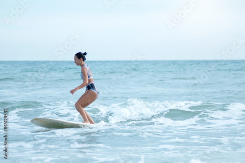 Asian surfing woman riding the waves on sunny day, outdoor activities, water sports activities concept photo