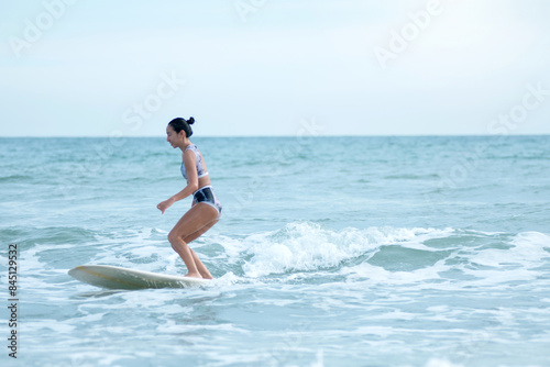 Asian surfing woman riding the waves on sunny day, outdoor activities, water sports activities concept