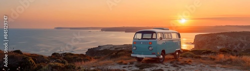 A vintage van parked at a coastal viewpoint overlooking the ocean as the sun sets, with travelers enjoying the view