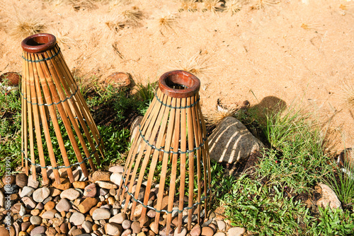 A rustic traditional bamboo fish trap, also known as bubu or lukah adorns the lawn, its woven structure showcasing traditional craftsmanship. Its weathered appearance adds charm to any outdoor space.