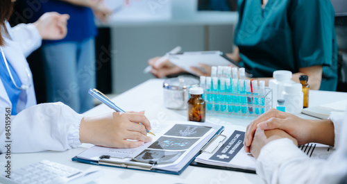 Medical team having a meeting with doctors in white lab coats and surgical scrubs seated