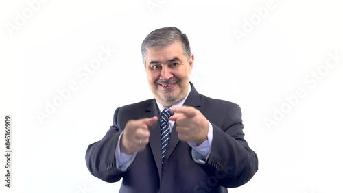 A confident businessman in a suit looks at the camera, smiles, and gestures thumbs up.
