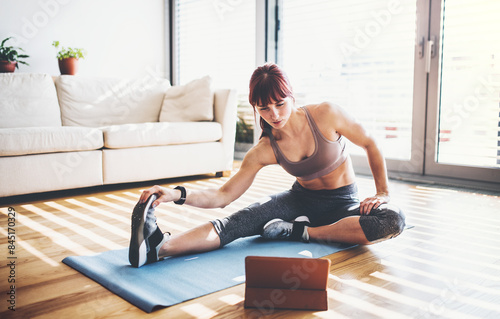 Beautiful redhead woman's home fitness routine. Home workout on gym mt in living room, sporty woman wearing sportswear.