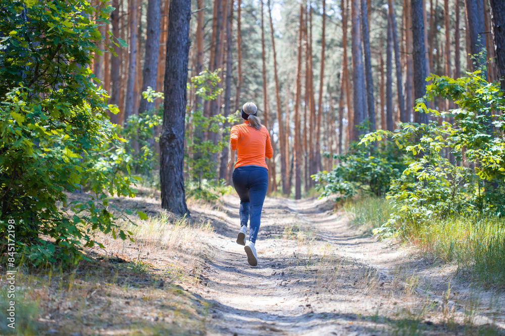 Fototapeta premium young girl on a morning run in a sunny pine forest