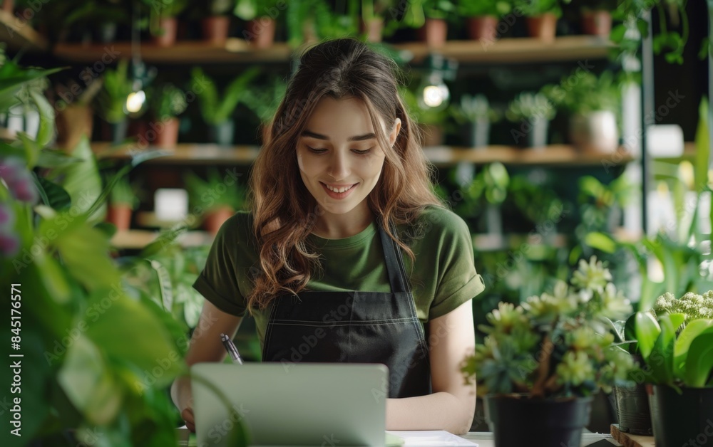A woman is sitting at a table with a laptop and a notebook. She is smiling and she is enjoying her work A woman is sitting at a table with a laptop and a notebook. She is smiling and she is enjoying her work