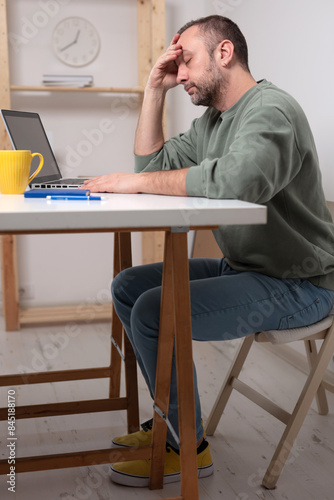 Man with headache while working on a laptop. photo