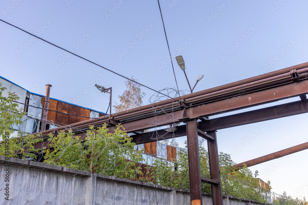 An overhead view of an industrial structure, showcasing a rusty metal pipe network supported by steel beams. The backdrop features a partly cloudy sky with the soft hues of a late afternoon.. An overhead view of an industrial structure, showcasing a rusty metal pipe network supported by steel beams. The backdrop features a partly cloudy sky with the soft hues of a late afternoon..