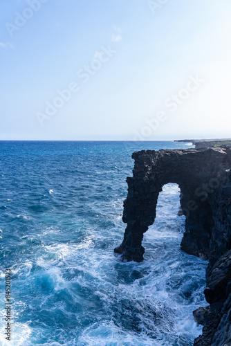 Hōlei Sea Arch is a 90-foot (27-meter)-high natural arch located in Hawaii, on the southern coast of the Big Island, south of Kīlauea. natural bridge of lava cliffs. photo