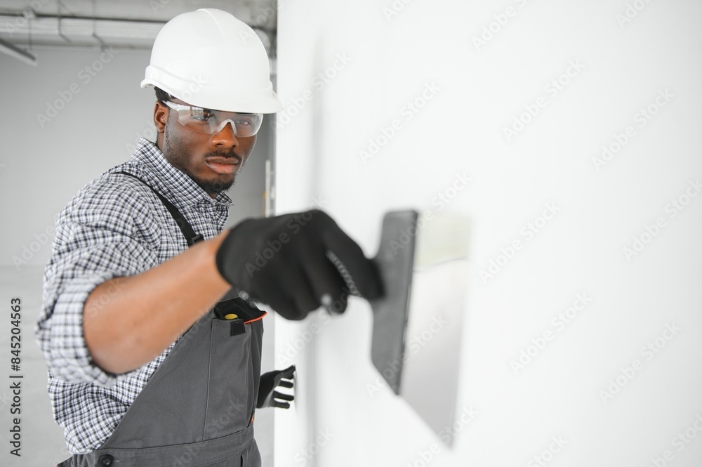 © Serhii - business, building, and people concept. african builder in hardhats with plastering tools indoors © Serhii - business, building, and people concept. african builder in hardhats with plastering tools indoors