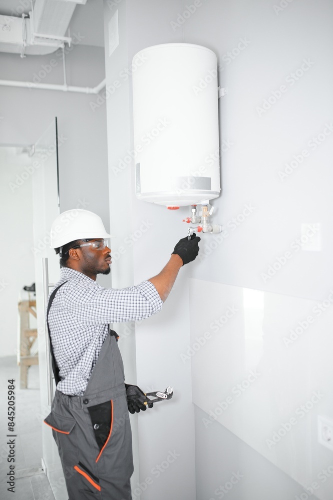 Young African Male Plumber Repairing Boiler Young African Male Plumber Repairing Boiler