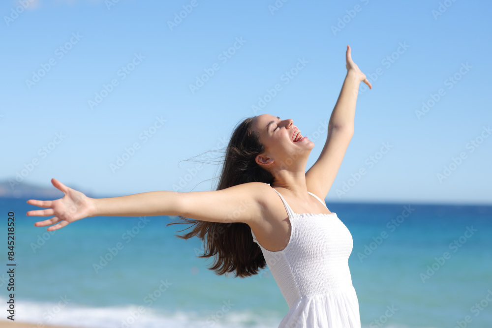 Joyful woman in white dress outstretching arms on the beach Joyful woman in white dress outstretching arms on the beach