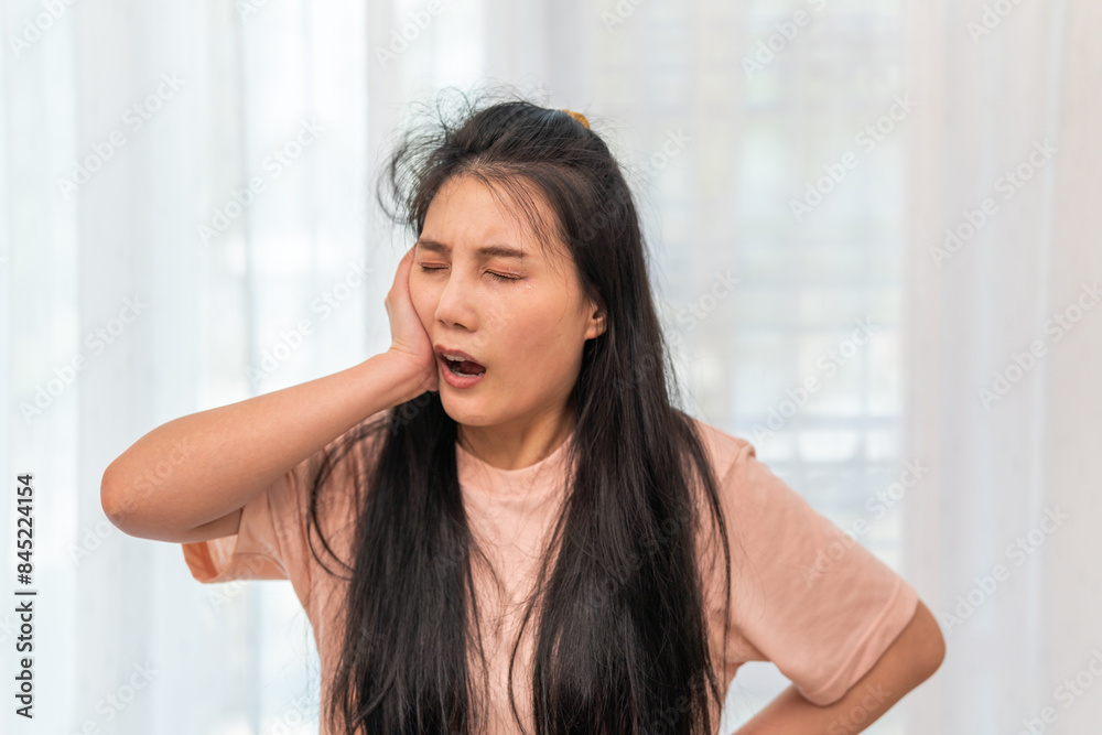Young asian woman experiencing tooth pain holding cheek with a distressed expression, pain commonly associated with dental issues, dental health, toothache, pain relief and medical care, dental care Young asian woman experiencing tooth pain holding cheek with a distressed expression, pain commonly associated with dental issues, dental health, toothache, pain relief and medical care, dental care