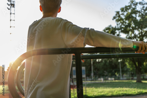 Man Leaning on Parallel Bars at a Sunny Outdoor Park