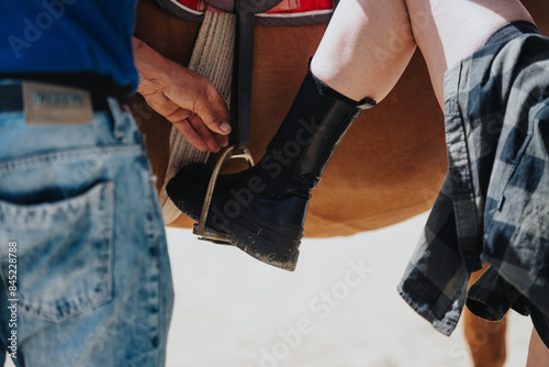 Papier peint Close-up of a person helping a rider adjust the stirrup while mounting a horse, emphasizing teamwork and equestrian preparation