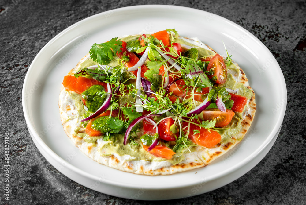 Colorful vegetable and salmon fish flatbread on a white plate, garnished with herbs. Ideal for culinary themes Colorful vegetable and salmon fish flatbread on a white plate, garnished with herbs. Ideal for culinary themes