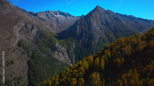 Saas Fee Saastal aerial drone Switzerland beautiful sunny blue sky autumn fall yellow Larchs forest trees Swiss Alps alpine mountain top glacier glacial peak gondola tram chairlift new circle left photo