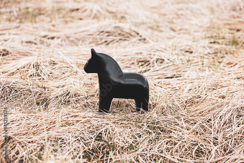 Принти на полотні A handmade figurine of a black horse in yellow dry grass is associated with stre