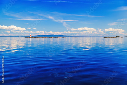 Lighthouse on a skerry in calm water photo