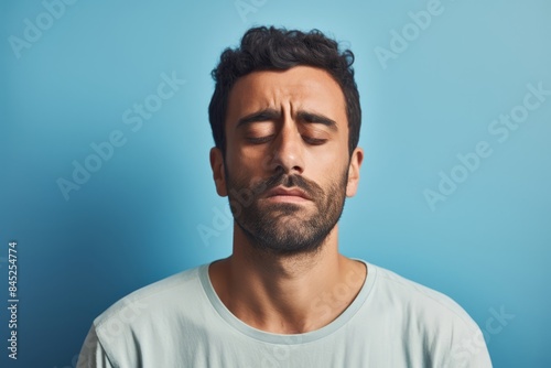 A sad man, 30, Middle Eastern, feeling insecure, on a pastel blue background  © Hanna Haradzetska