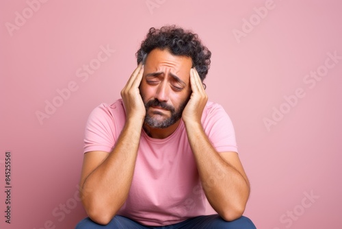 The sad man, 33, Middle Eastern, feeling isolated, on a pastel light pink background 
