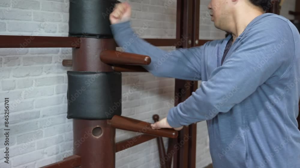 man training in Wing Chun Kung Fu with wooden dummy. The athlete shows techniques Wing Chun KungFu wooden dummy.	