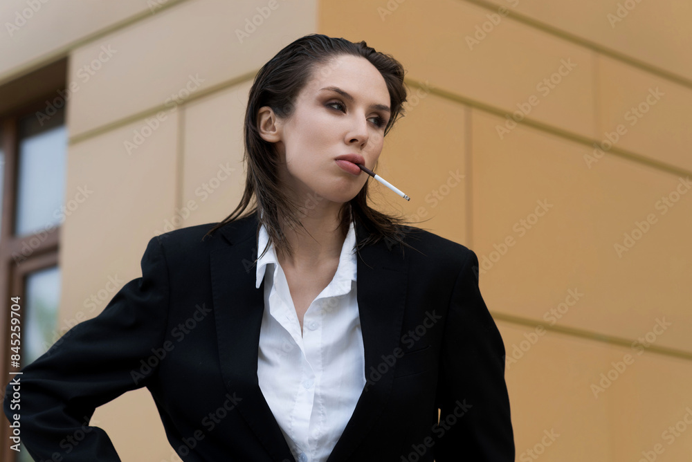Attractive caucasian young woman in suit smoking cigarette, posing while walking outdoors on spring day. Sexy, stylish and elegant lady. Fashion, Lifestyle. Attractive caucasian young woman in suit smoking cigarette, posing while walking outdoors on spring day. Sexy, stylish and elegant lady. Fashion, Lifestyle.