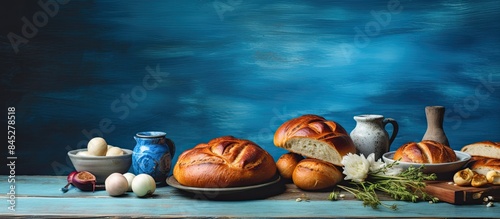On an old blue wooden table there is a beautiful arrangement of challah painted eggs and sliced pork creating a captivating copy space image photo