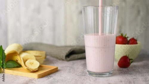 Pouring pink berry smoothie in glass. Healthy summer drink, berry milkshake or smoothi photo