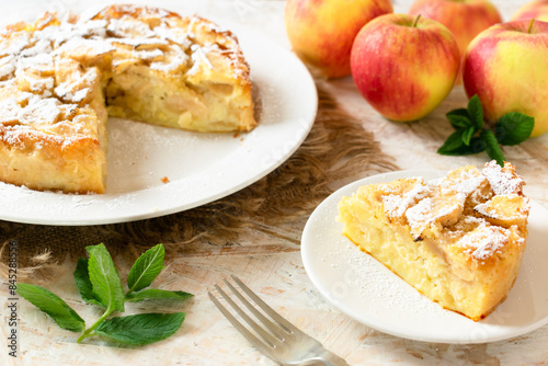 Easy Italian apple cake on a white dish, with red apples in the background.