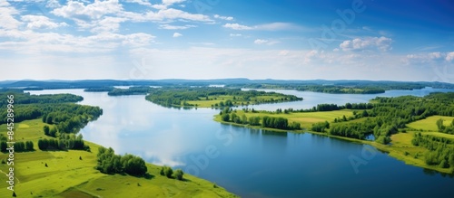 Drone captures top view of a stunning summer landscape with a serene blue lake nestled in a vibrant green field providing a picturesque nature background with ample copy space