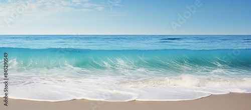 A serene blue sea wave crashes against the sandy beach creating a refreshing backdrop for a relaxing summer holiday The image offers ample copy space