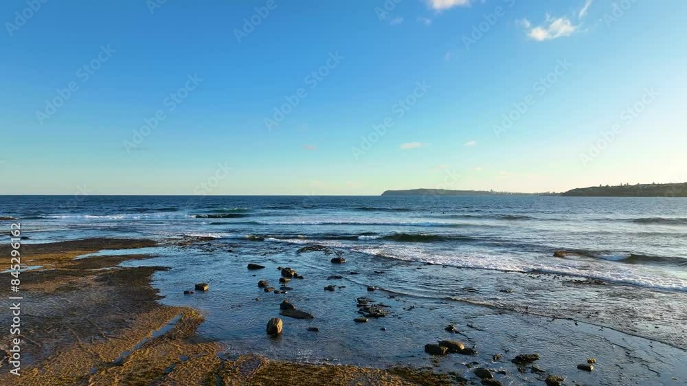 Aerial view of Longreef coast with turquoise water and rocky coastline in Sydney, Australia. Drone view of rugged shoreline, flying low over the ocean waves towards surf Aerial view of Longreef coast with turquoise water and rocky coastline in Sydney, Australia. Drone view of rugged shoreline, flying low over the ocean waves towards surf