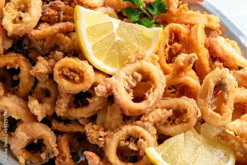 Primo piano di anelli di calamari fritti dorati e croccanti, cibo italiano, cucina mediterranea  photo