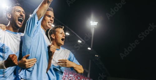 Professional football players celebrating a winning goal at a championship match in a full stadium photo